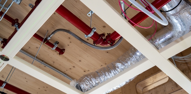 Leidingwerk onder het houten plafond van The CubeHouse