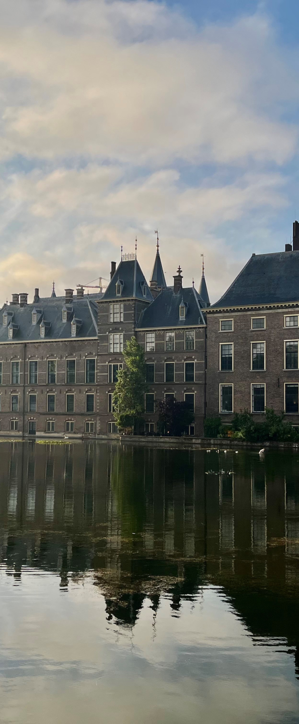 Afbeelding van het Binnenhof Den Haag vanaf de Hofvijver bij zonsopkomst