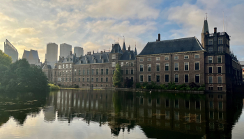 Afbeelding van het Binnenhof Den Haag vanaf de Hofvijver bij zonsopkomst