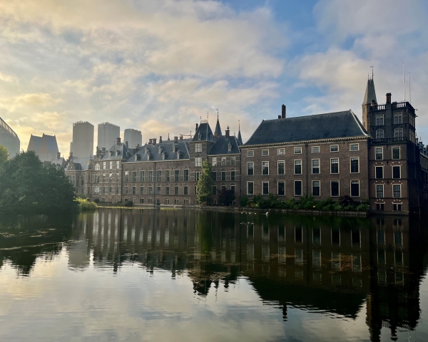 Afbeelding van het Binnenhof Den Haag vanaf de Hofvijver bij zonsopkomst