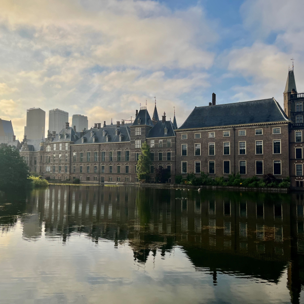 Afbeelding van het Binnenhof Den Haag vanaf de Hofvijver bij zonsopkomst